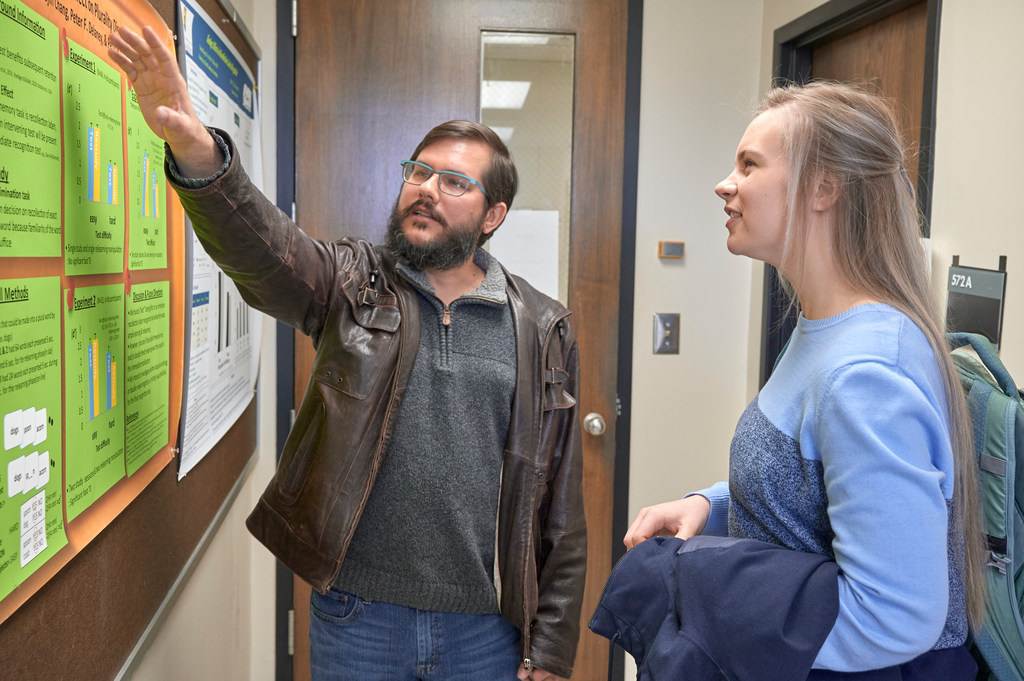 professor pointing at a poster standing next to a student