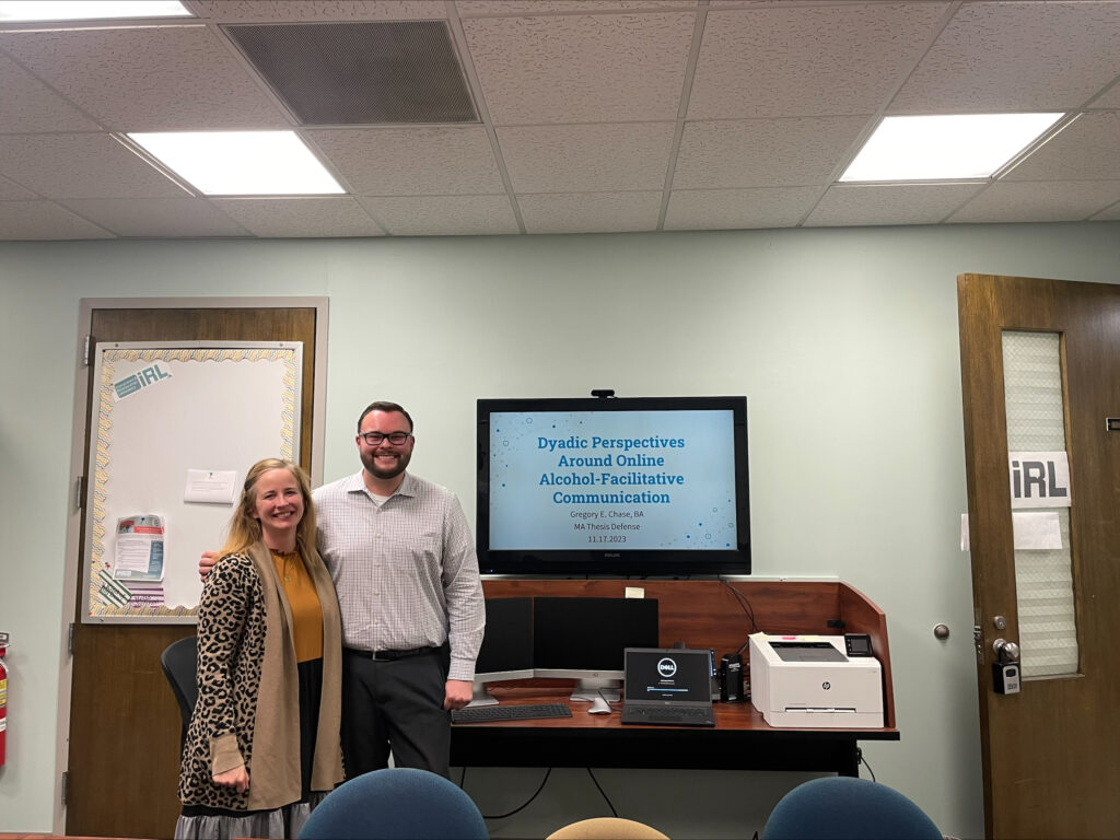 Photo of Chase and Jensen in front of a screen with this thesis talk title slide.
